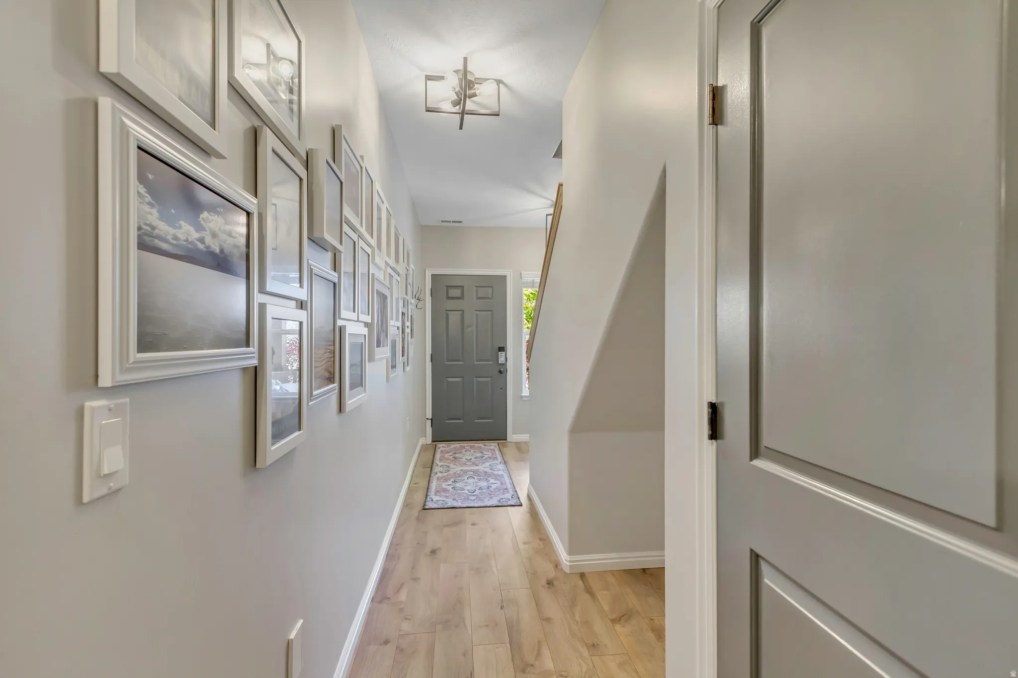 Entryway featuring wood-finish flooring, light gray walls, a contemporary ceiling light fixture, and a paneled front door