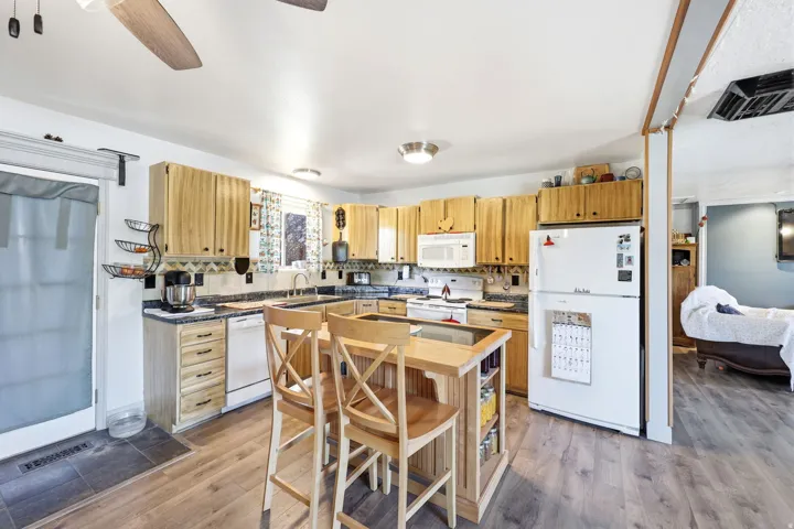 Kitchen featuring wood-finish cabinetry, dark countertops, a central island with integrated seating, and wood-finish flooring