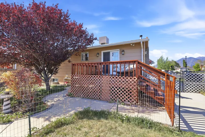Rear exterior featuring a spacious wood deck with lattice screening, an exterior light fixture, and a sliding glass door