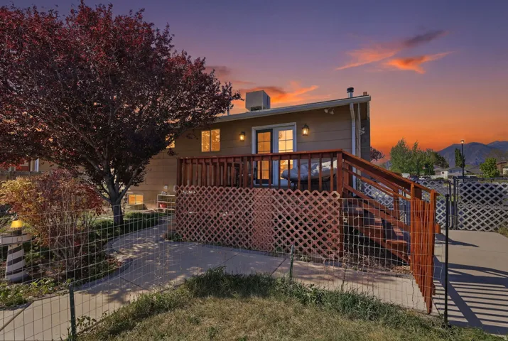 Rear exterior featuring a spacious wood deck, privacy lattice, and a concrete patio
