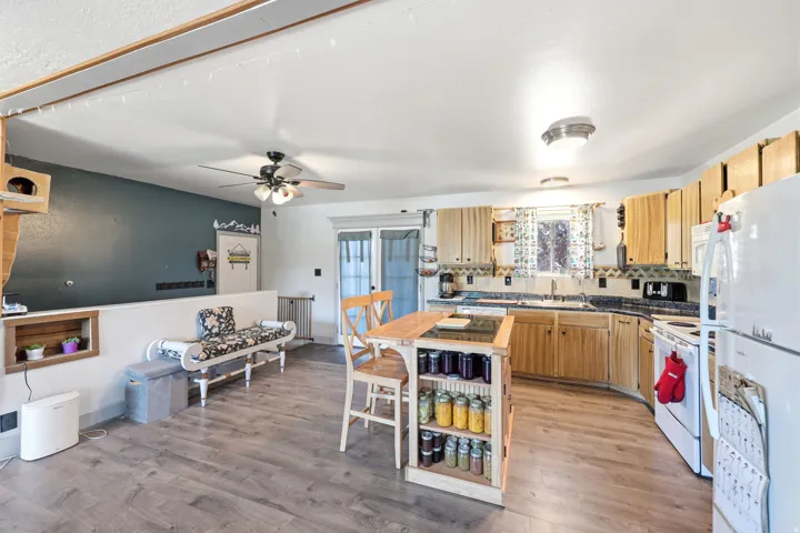 Kitchen featuring natural wood-finish cabinetry, a central island with integrated storage, wood-finish flooring, a ceiling fan with light fixture, and a window with a sink below