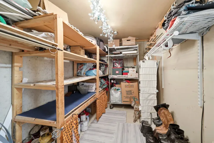 Dedicated storage area featuring built-in wooden shelving, metal wire shelving, and a concrete foundation wall