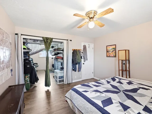 Bedroom featuring wood-finish flooring, a ceiling fan with integrated lighting, and a closet with bifold doors