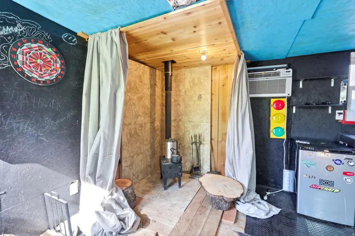 Compact interior space featuring a built-in wood-burning stove with a visible flue, a window air conditioning unit, and a mini-refrigerator