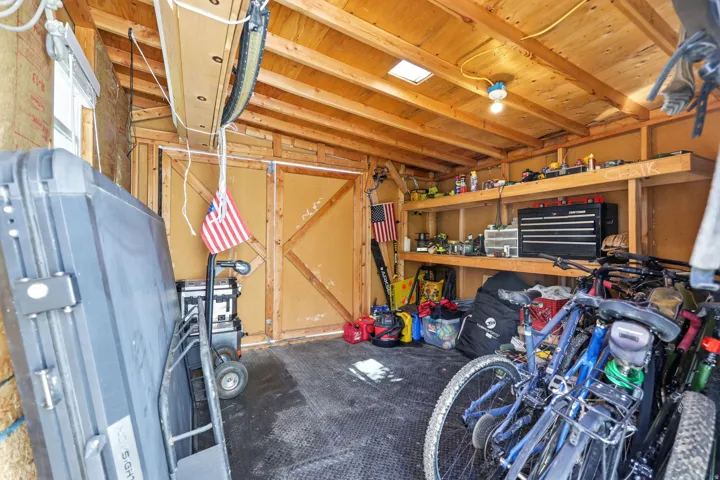 Utility shed featuring wood-frame construction, exposed wood ceiling beams, built-in shelving, and a durable rubberized floor