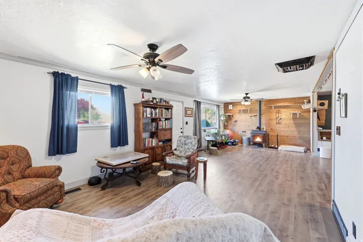 Spacious interior room featuring wood-finish flooring, white walls, and a warm wood accent wall