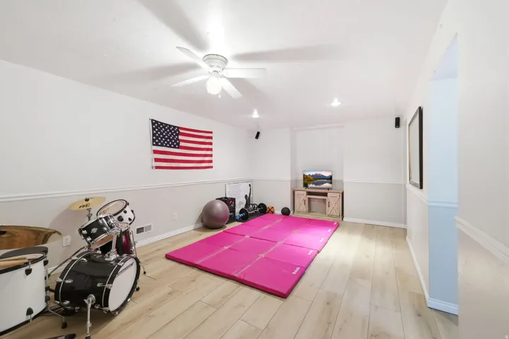 Spacious room featuring light wood-finish flooring, recessed lighting, a ceiling fan, and two-tone wall finishes with chair rail molding