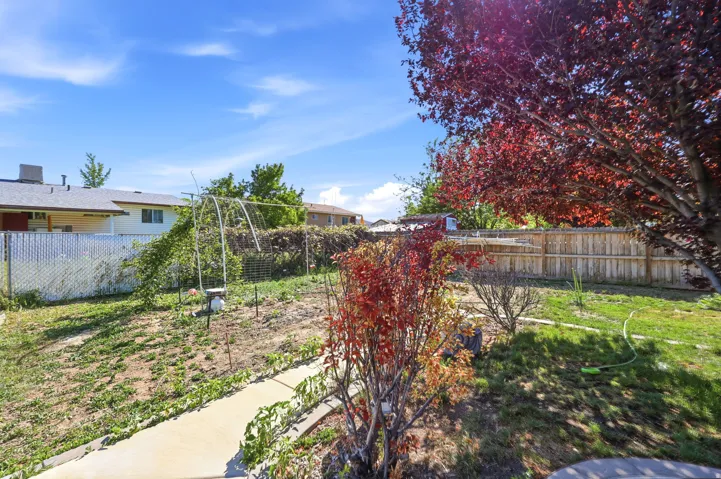 Spacious backyard featuring a concrete pathway, a privacy fence, and mature trees