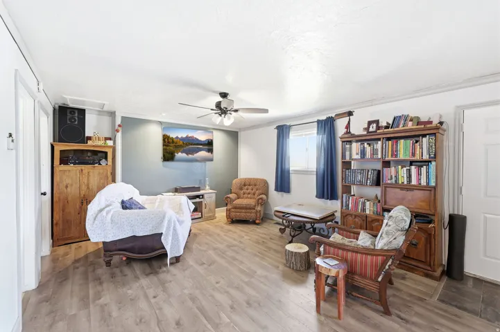 Spacious room featuring wood-finish flooring, a ceiling fan with light fixture, and a window with natural light