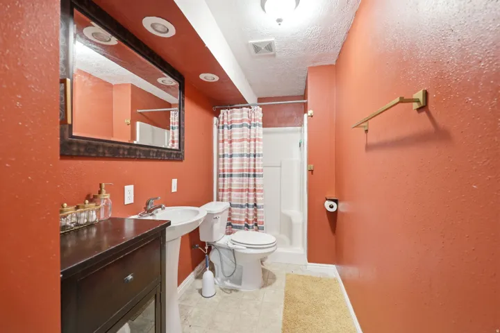 Bathroom featuring a pedestal sink, a toilet, and a shower with a shower curtain