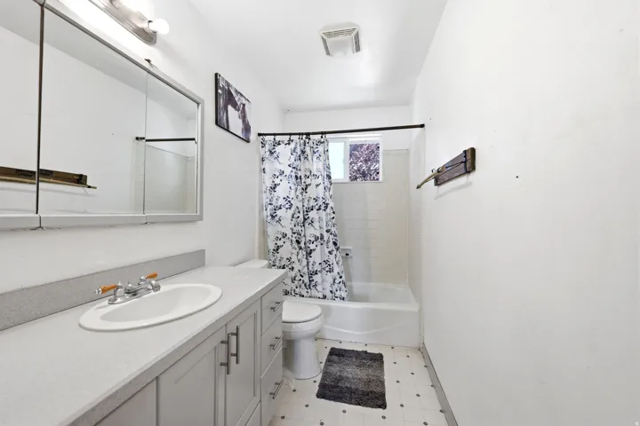 Bathroom featuring a vanity with a white oval sink, chrome faucet, and gray cabinetry
