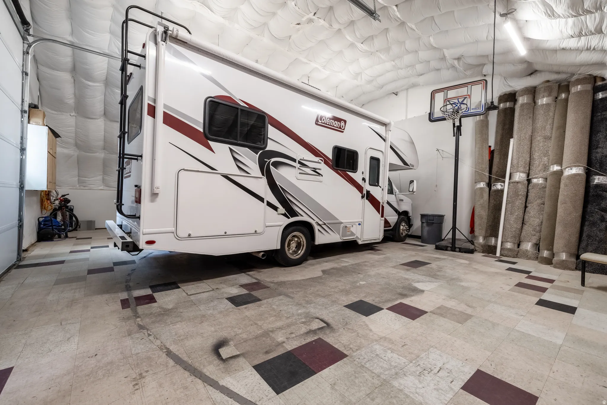 Spacious garage featuring high ceilings with insulation, overhead fluorescent lighting, and a roll-up garage door