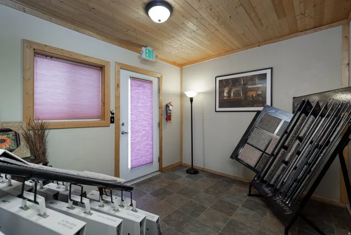Tiled flooring with wood-finish ceiling, featuring a window and door with privacy blinds