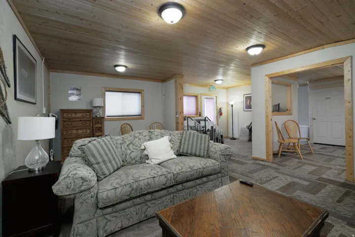 Spacious common area featuring wood-finish plank ceiling, light-toned walls, and wood-trim doorways