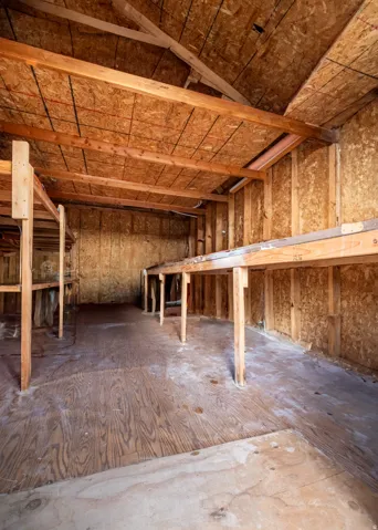 Unfinished interior space featuring exposed wood framing, oriented strand board walls, and plywood flooring