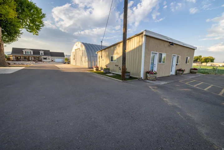 Paved entry with a stucco and siding structure, an arched metal building, and a traditional-style dwelling