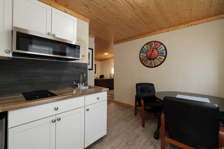 Compact kitchen area featuring white shaker-style cabinetry, wood-finish countertops, and a built-in stainless steel microwave