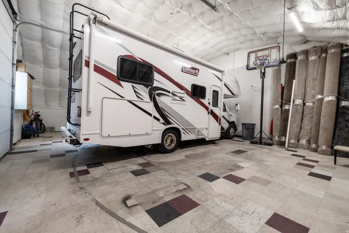 Spacious garage featuring high ceilings with insulation, overhead fluorescent lighting, and a roll-up garage door