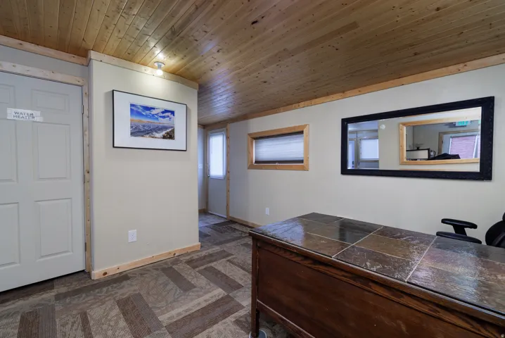 Entry area featuring wood-finish ceiling panels, light-toned walls, and geometric pattern flooring