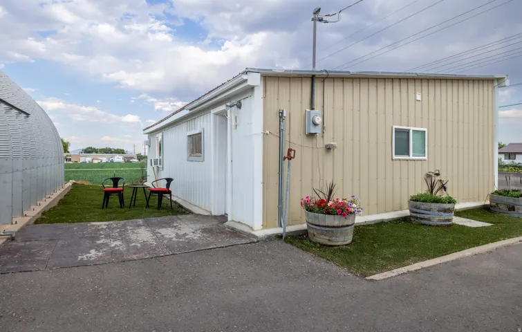 Exterior featuring vertical siding, a window unit, and a paved area