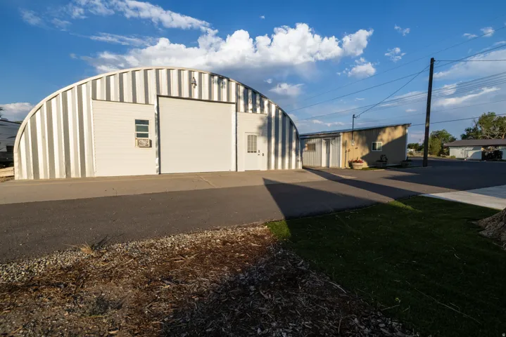 Quonset hut style structure featuring corrugated metal siding and a large roll-up door