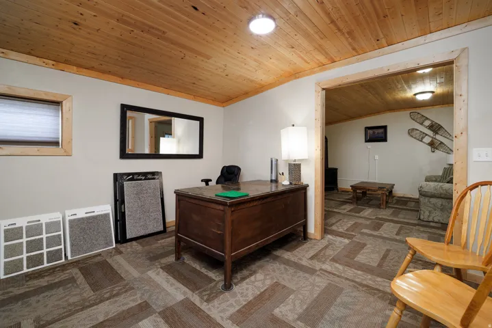Room featuring a wood-finish plank ceiling and patterned carpet tile flooring