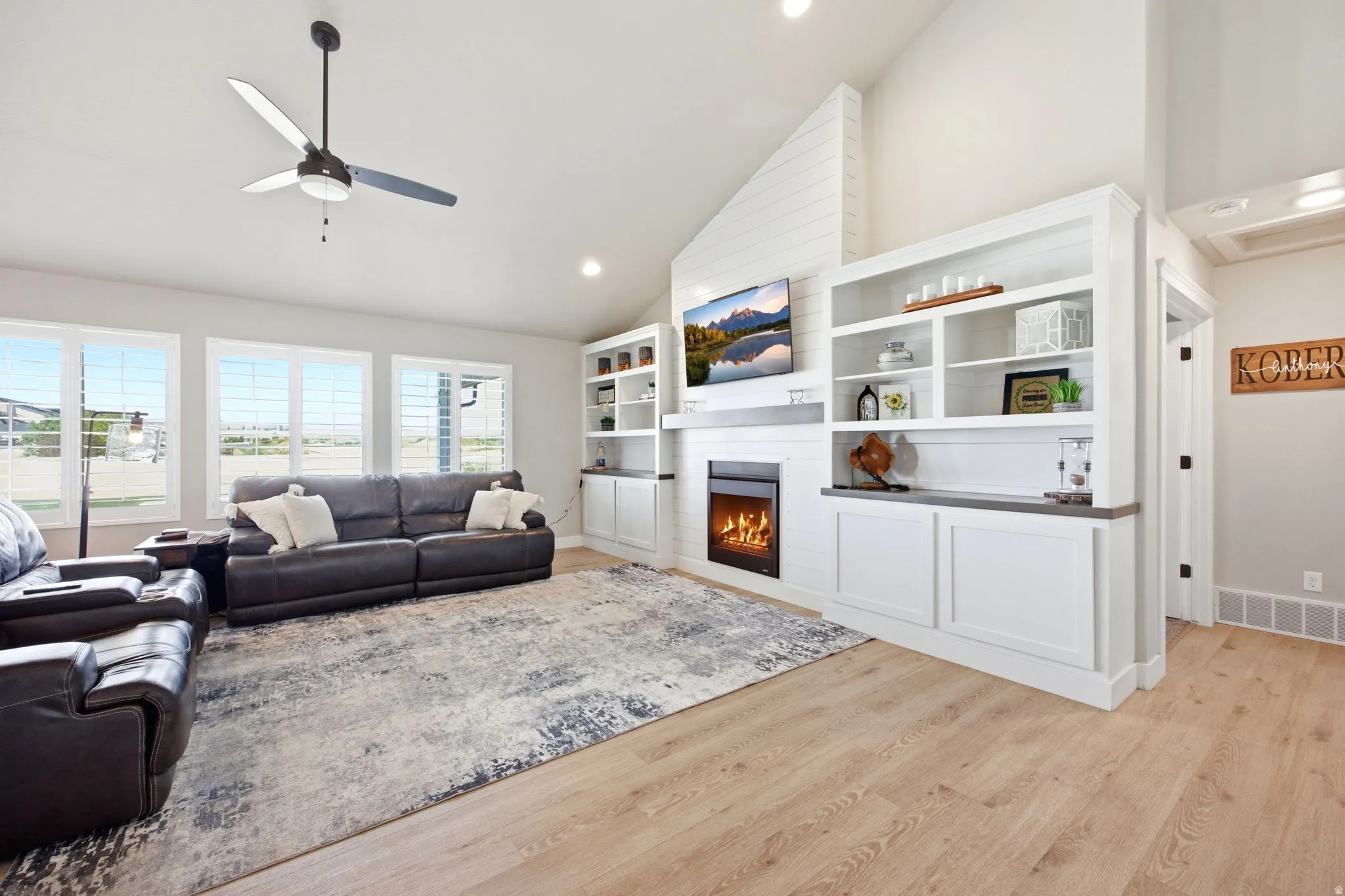 Spacious living area featuring high vaulted ceilings, wood-finish flooring, and a contemporary ceiling fan