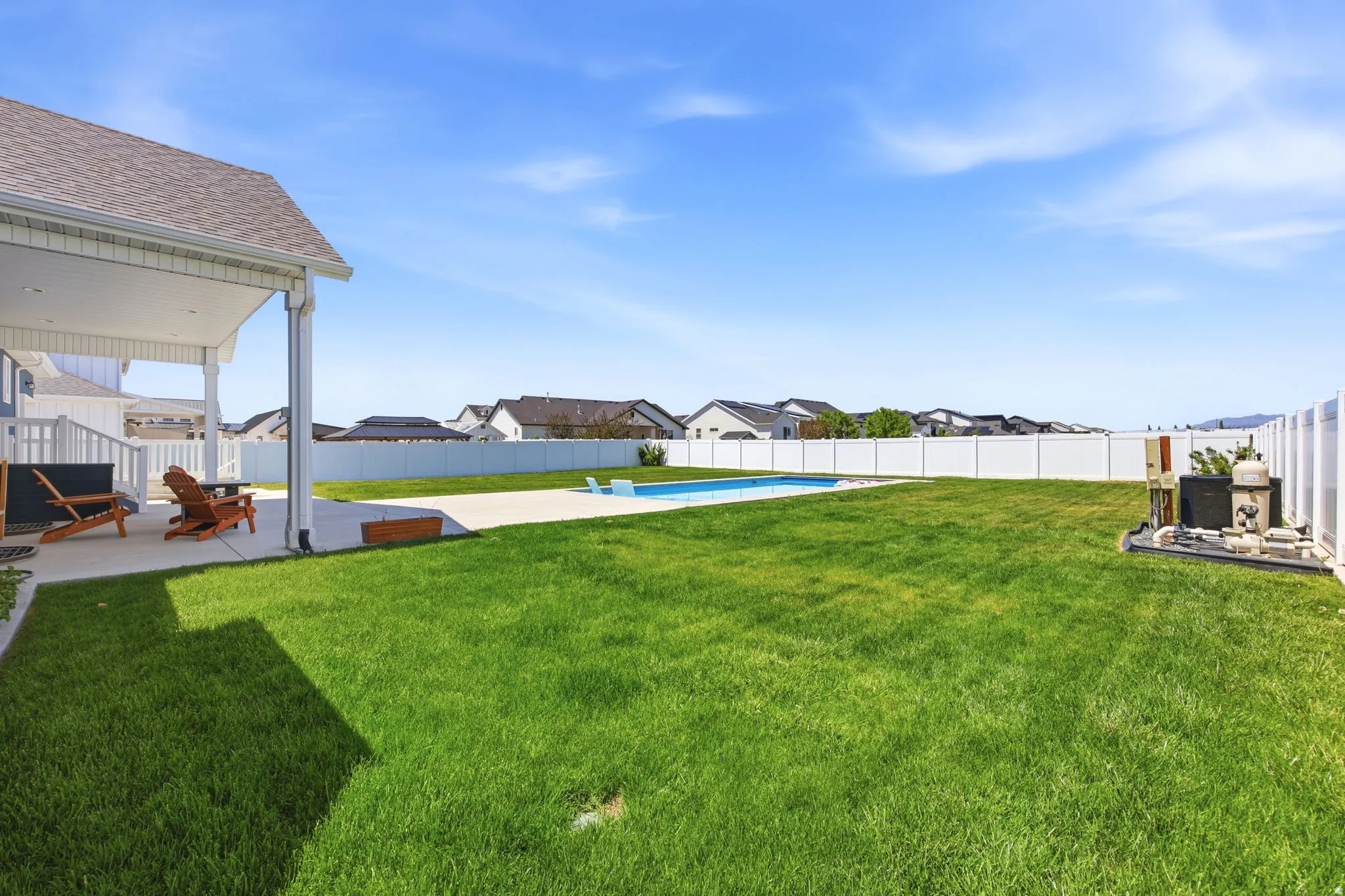 Expansive backyard featuring a manicured lawn, a swimming pool, and a concrete patio