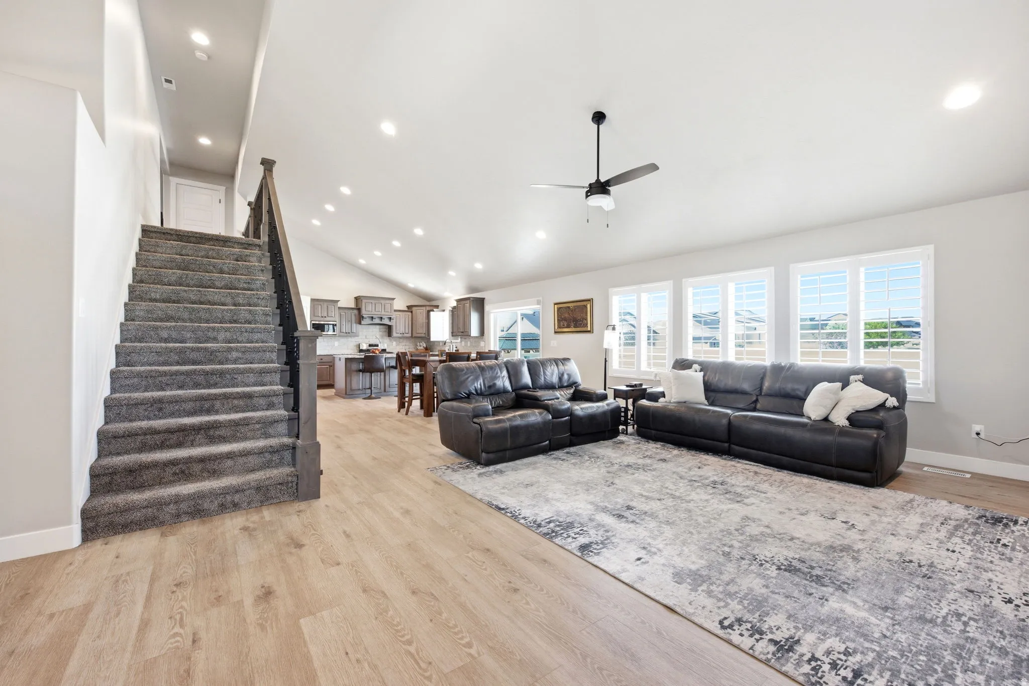 Open-concept living space featuring vaulted ceilings, recessed lighting, and wood-finish flooring