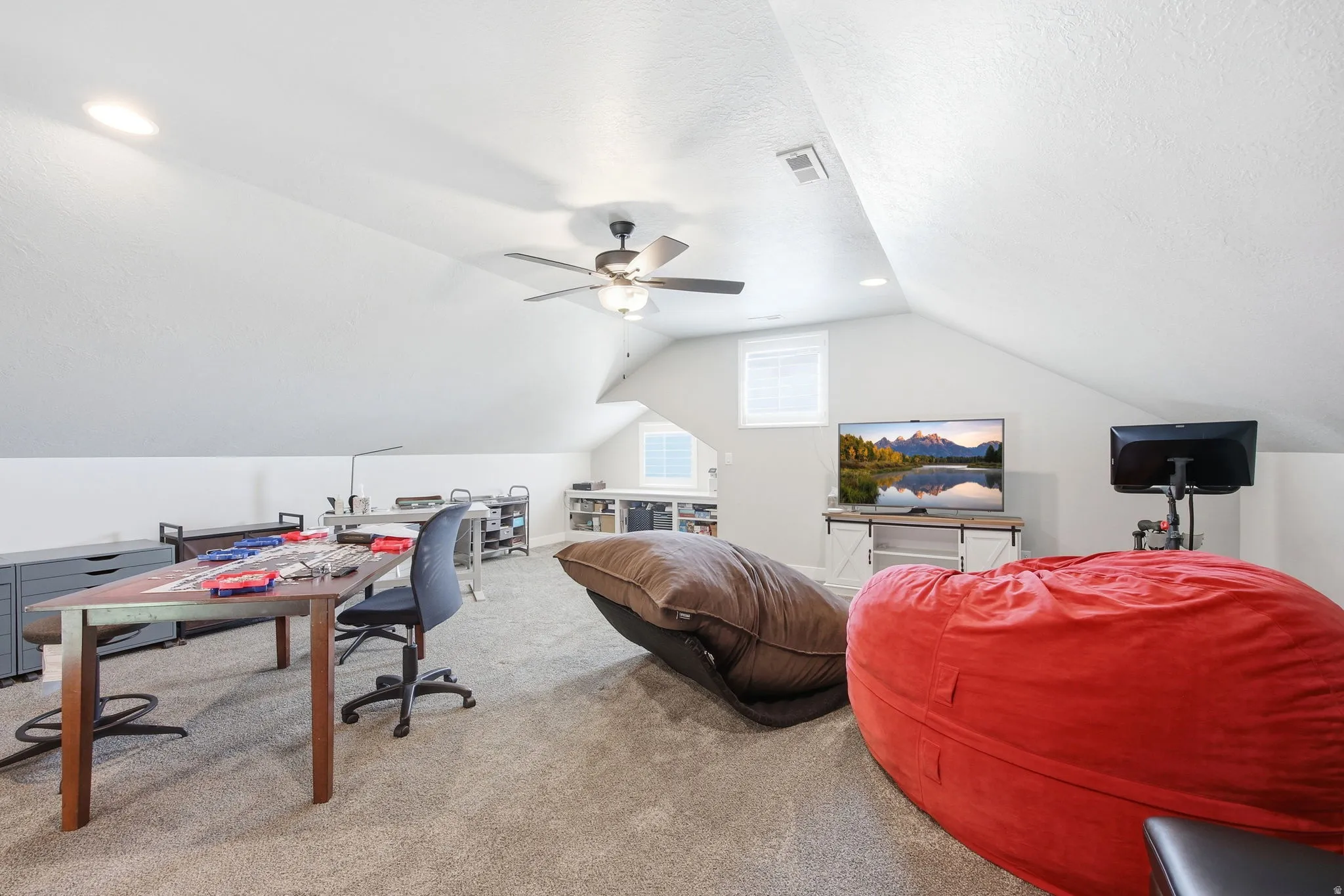 Spacious upper-level bonus room featuring sloped ceilings, recessed lighting, and a ceiling fan