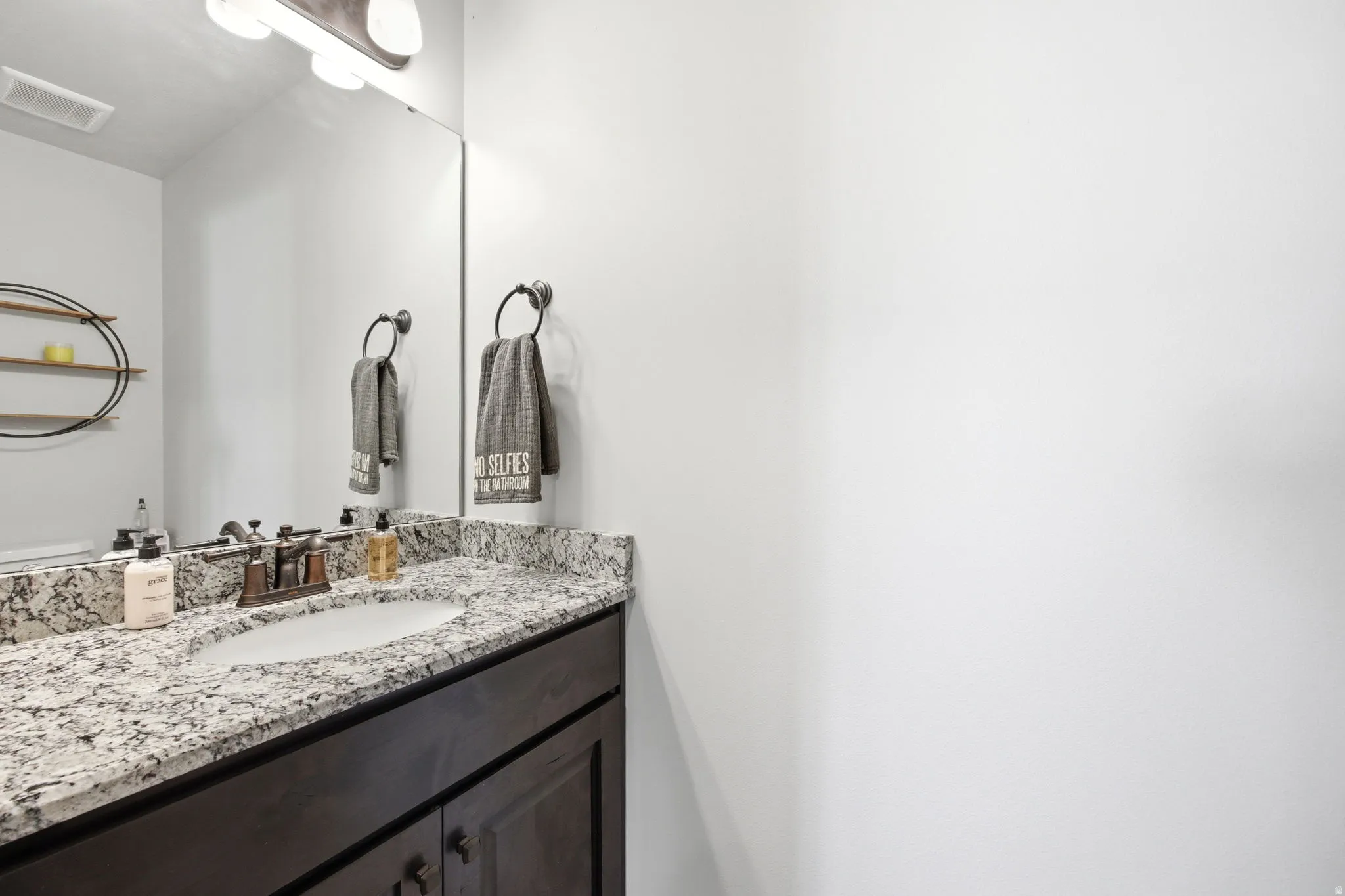 Vanity featuring a stone countertop, an undermount sink, and a bronze-finish faucet
