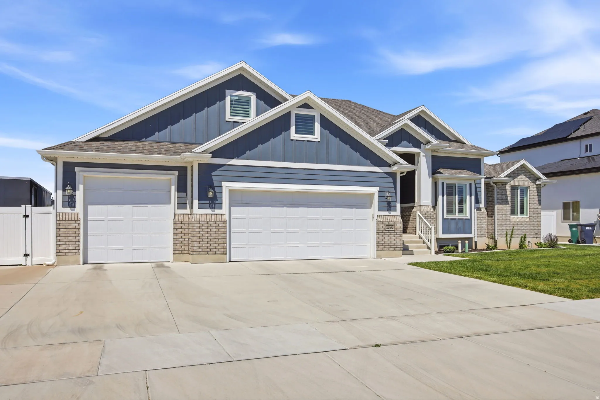 Contemporary residence featuring blue siding, light brick accents, and a multi-car concrete driveway