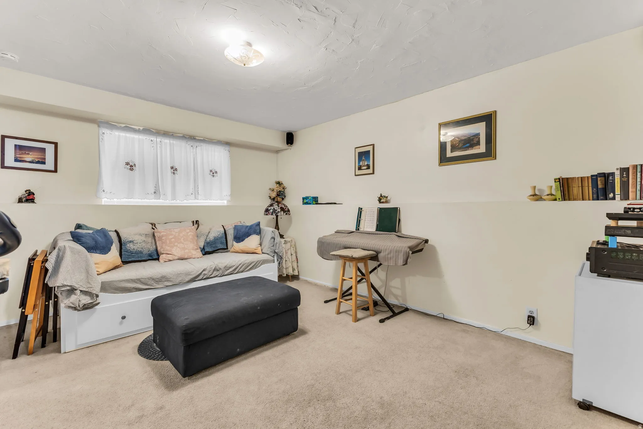 Carpeted interior space with a window featuring white curtains