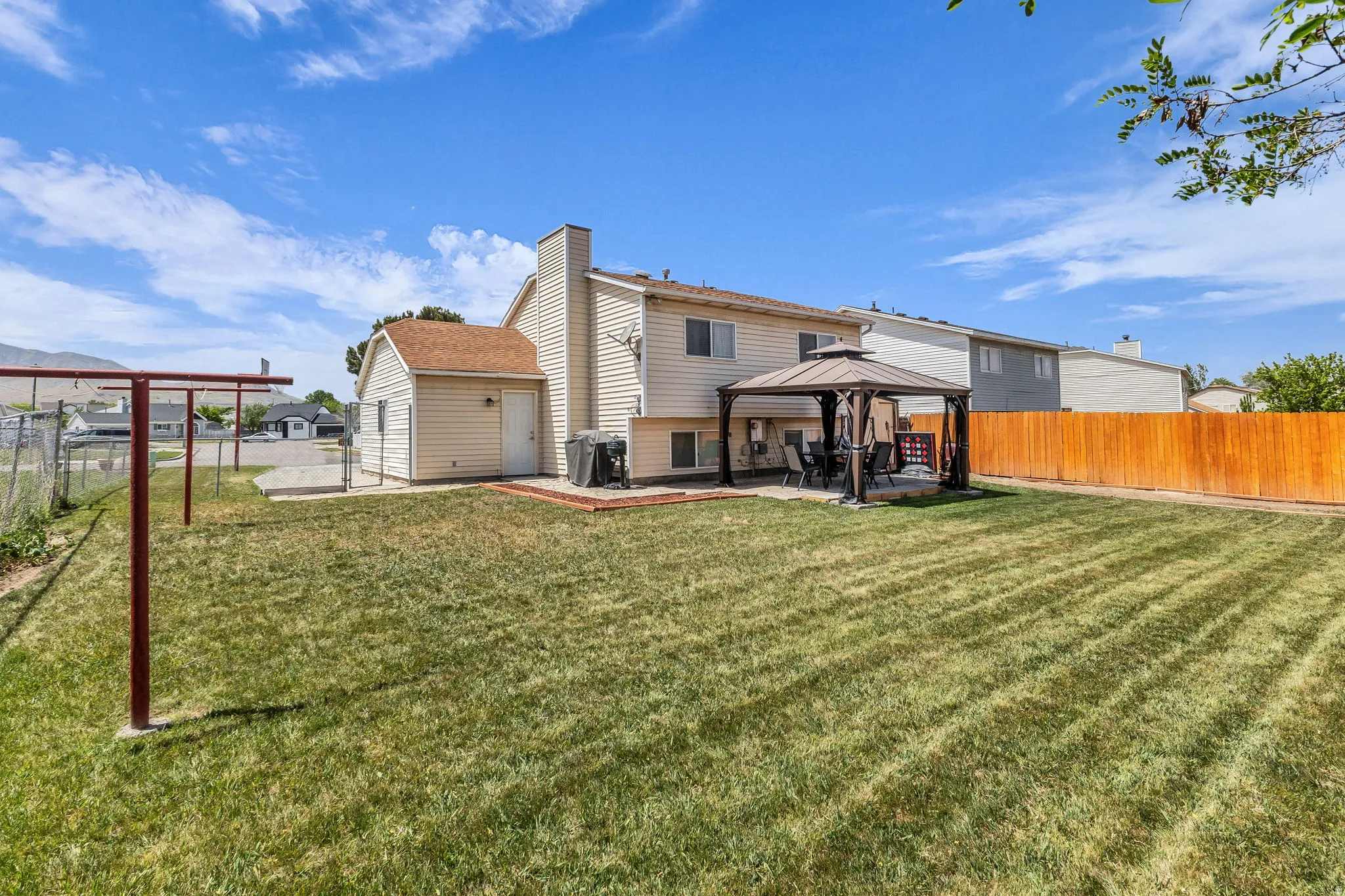 Expansive backyard with a manicured lawn, a detached storage shed, and a covered patio area