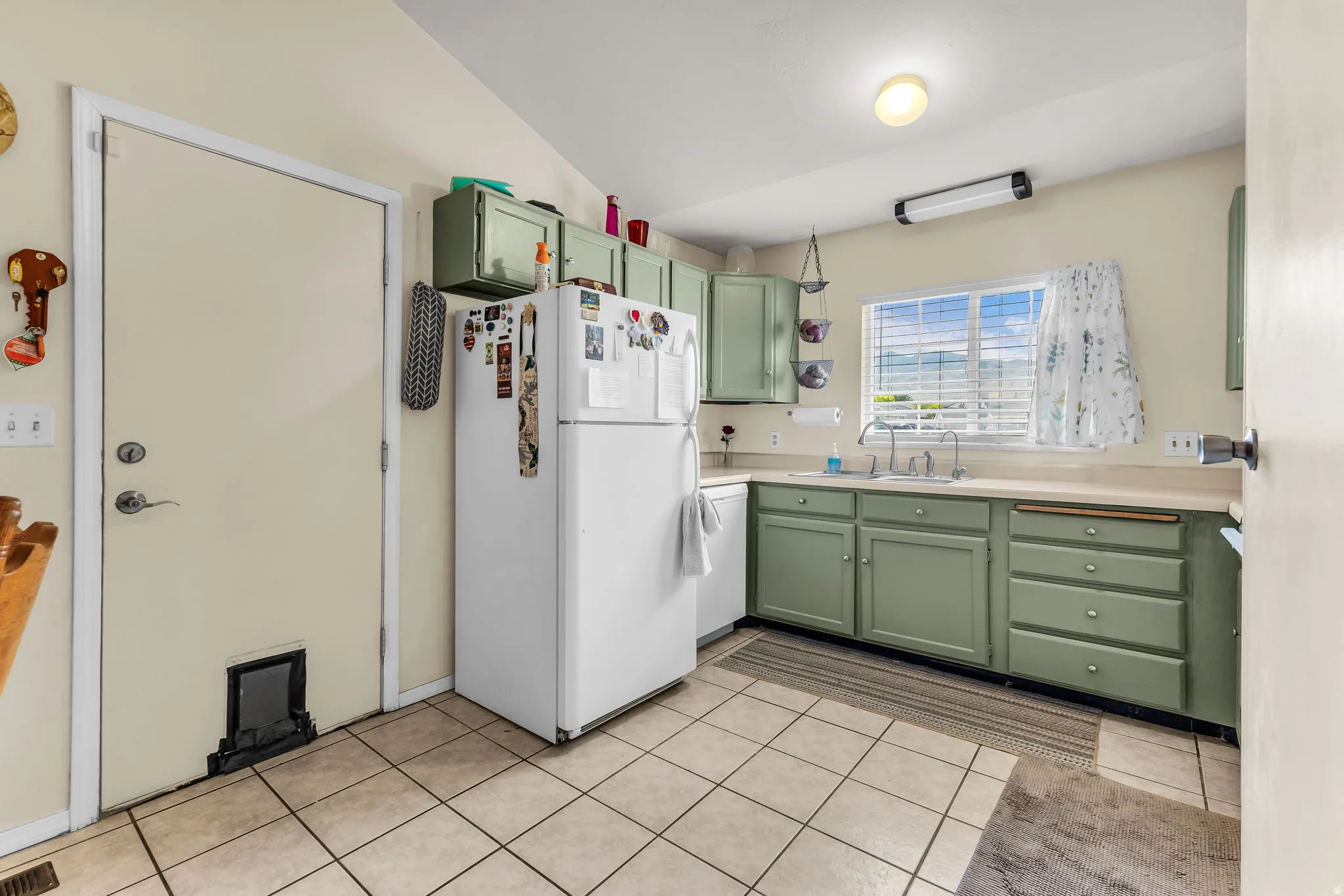 Kitchen featuring tile flooring, painted cabinetry, and a double basin sink under a window