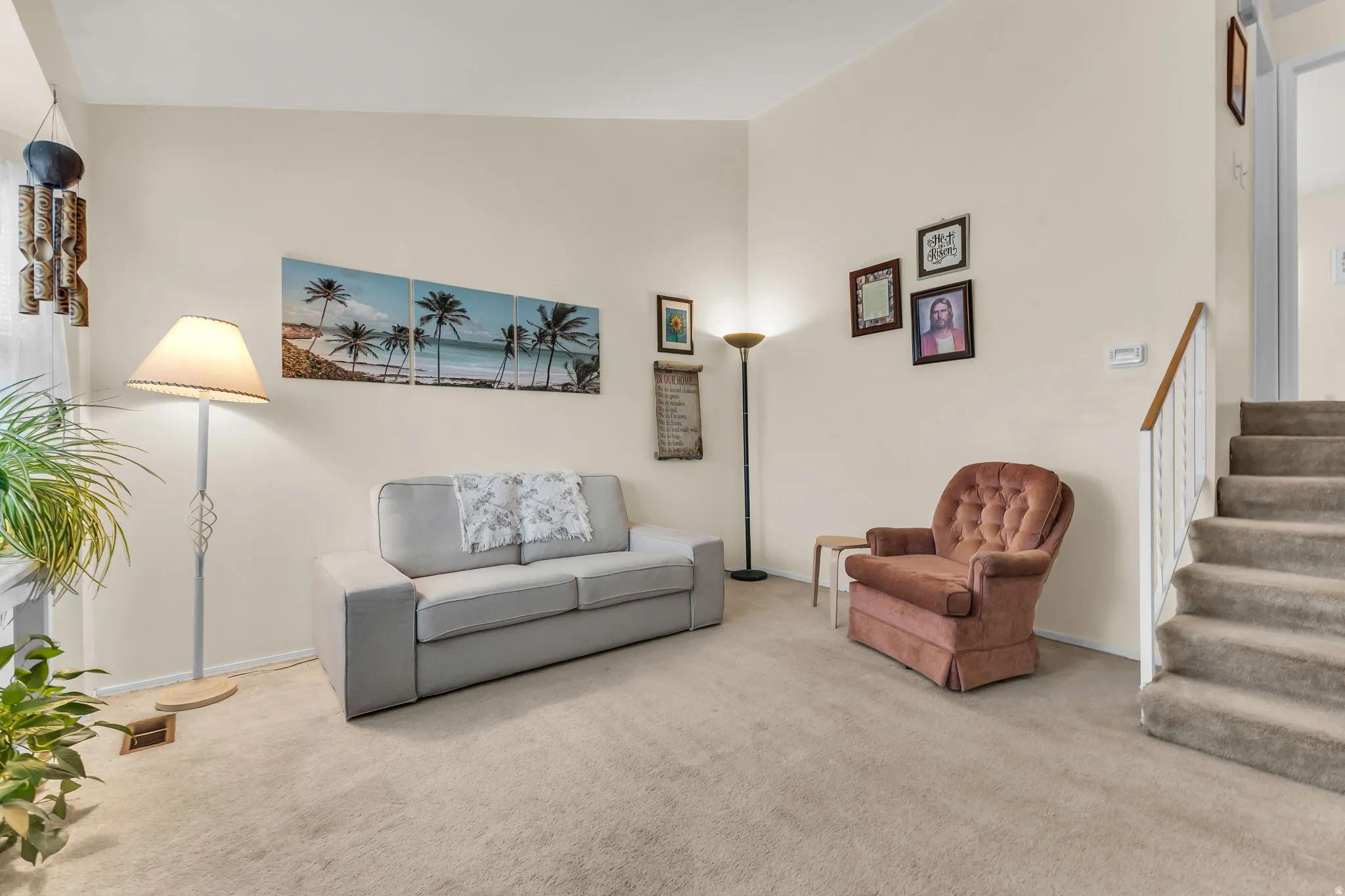 Carpeted living area featuring vaulted ceilings, a staircase with white painted balusters and a wood-finish handrail, and light neutral wall colors