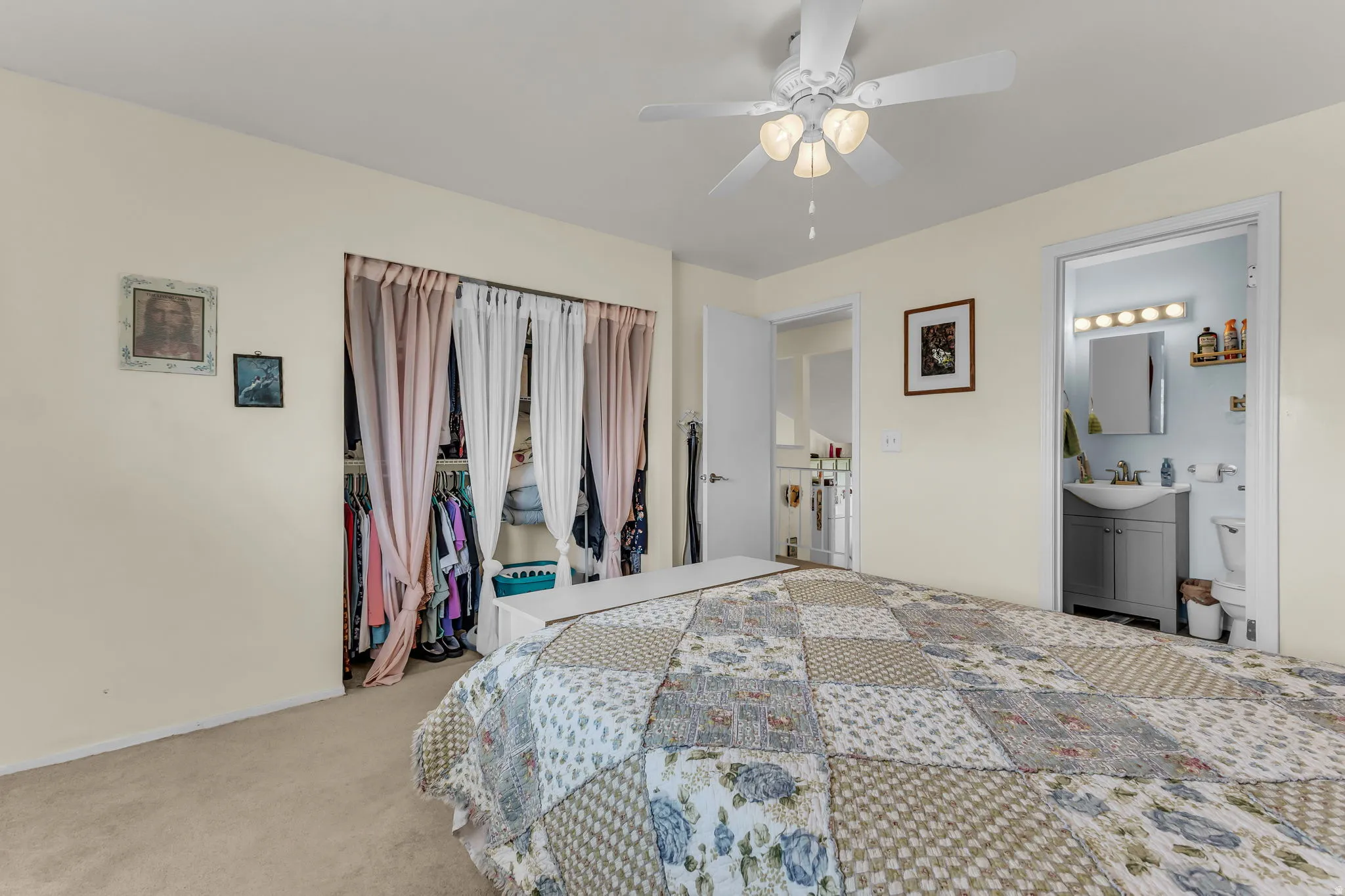 Carpeted bedroom featuring a ceiling fan with light fixture, an open closet with curtain dividers, and direct access to a full bathroom