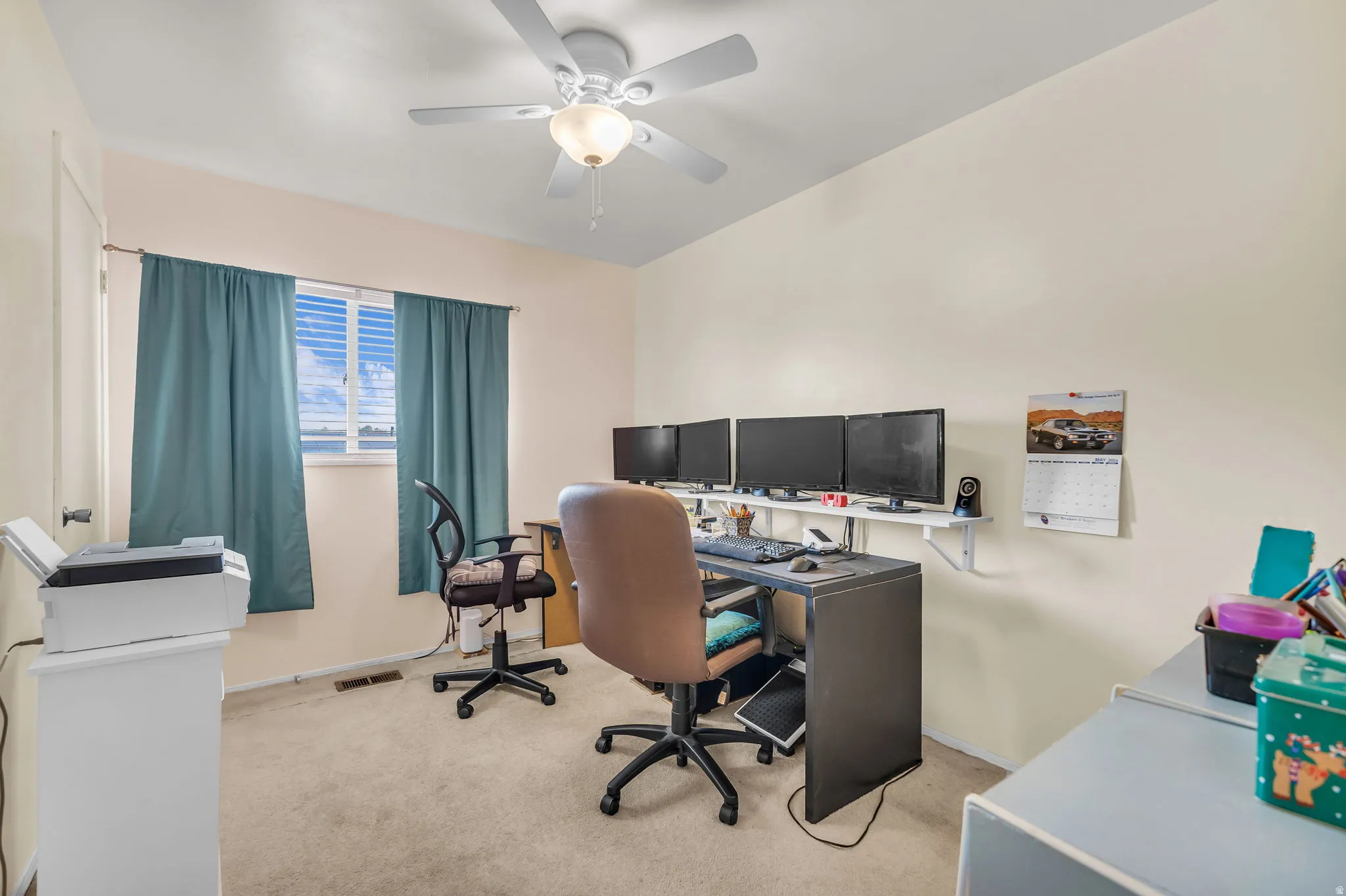 Carpeted room with a ceiling fan light fixture and neutral-toned walls