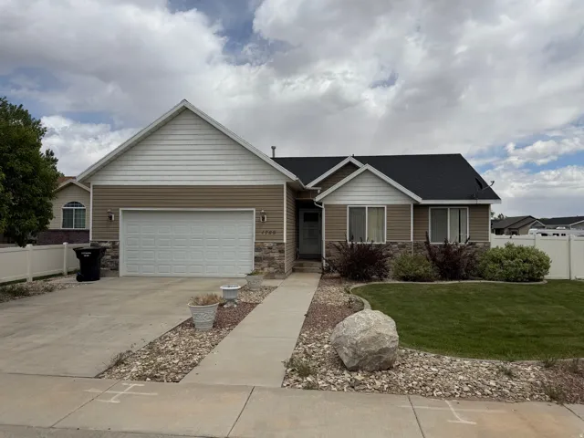 Single-story residence featuring a two-car garage, stone and siding exterior, concrete driveway, and a front walkway