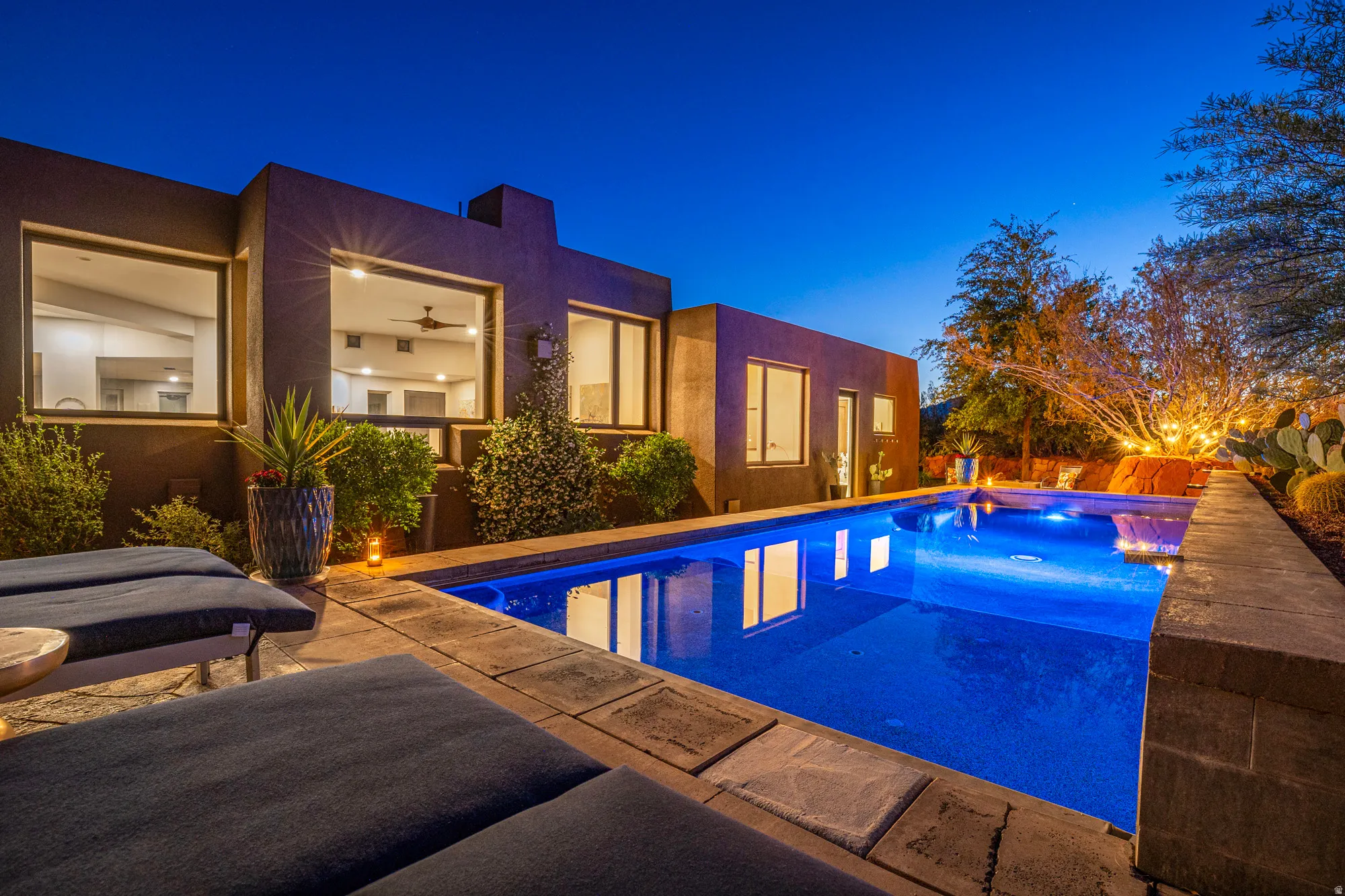Modern home exterior with a rectangular swimming pool, stone coping, and desert landscaping