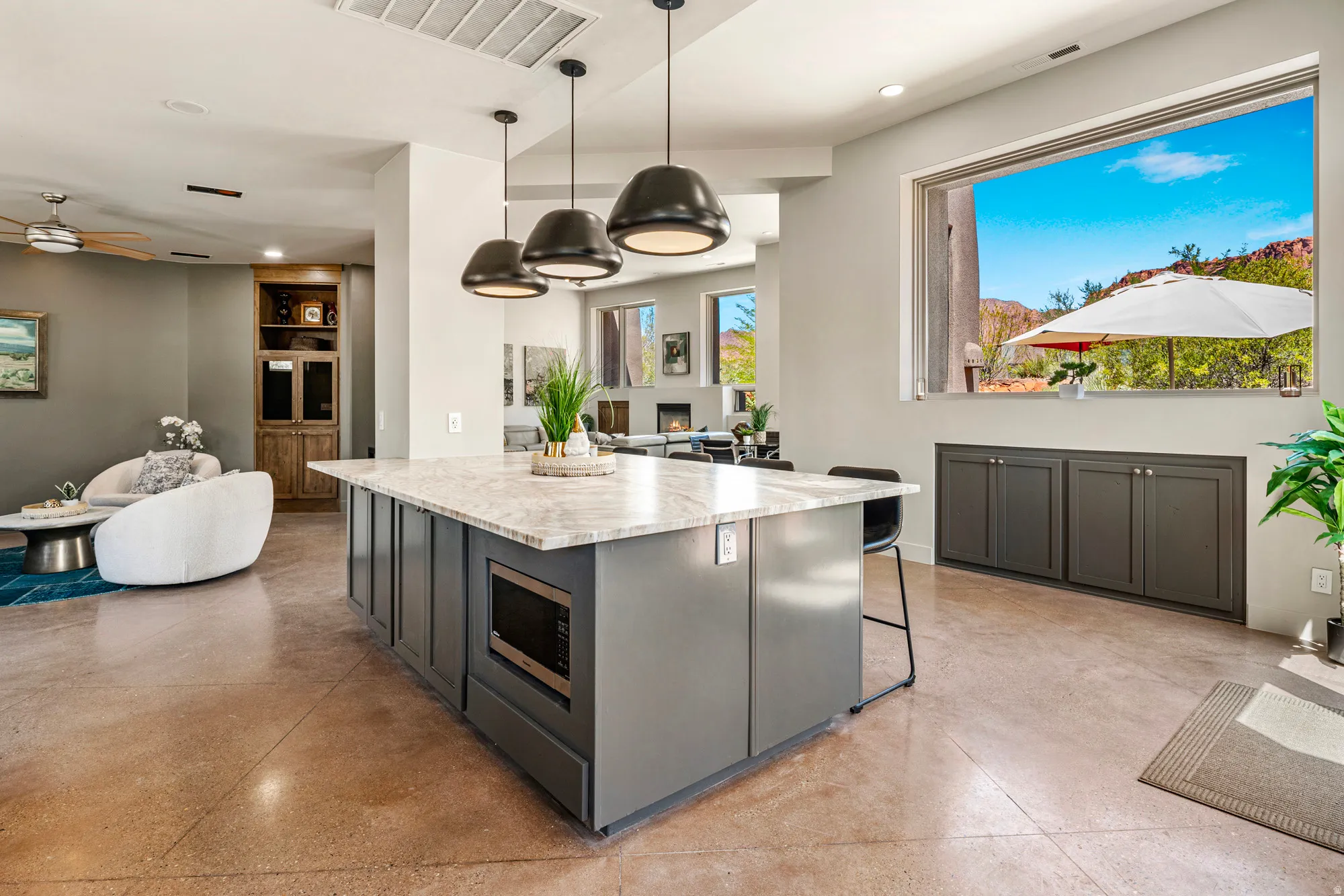 Kitchen island with a light-toned countertop, integrated microwave, and pendant lighting