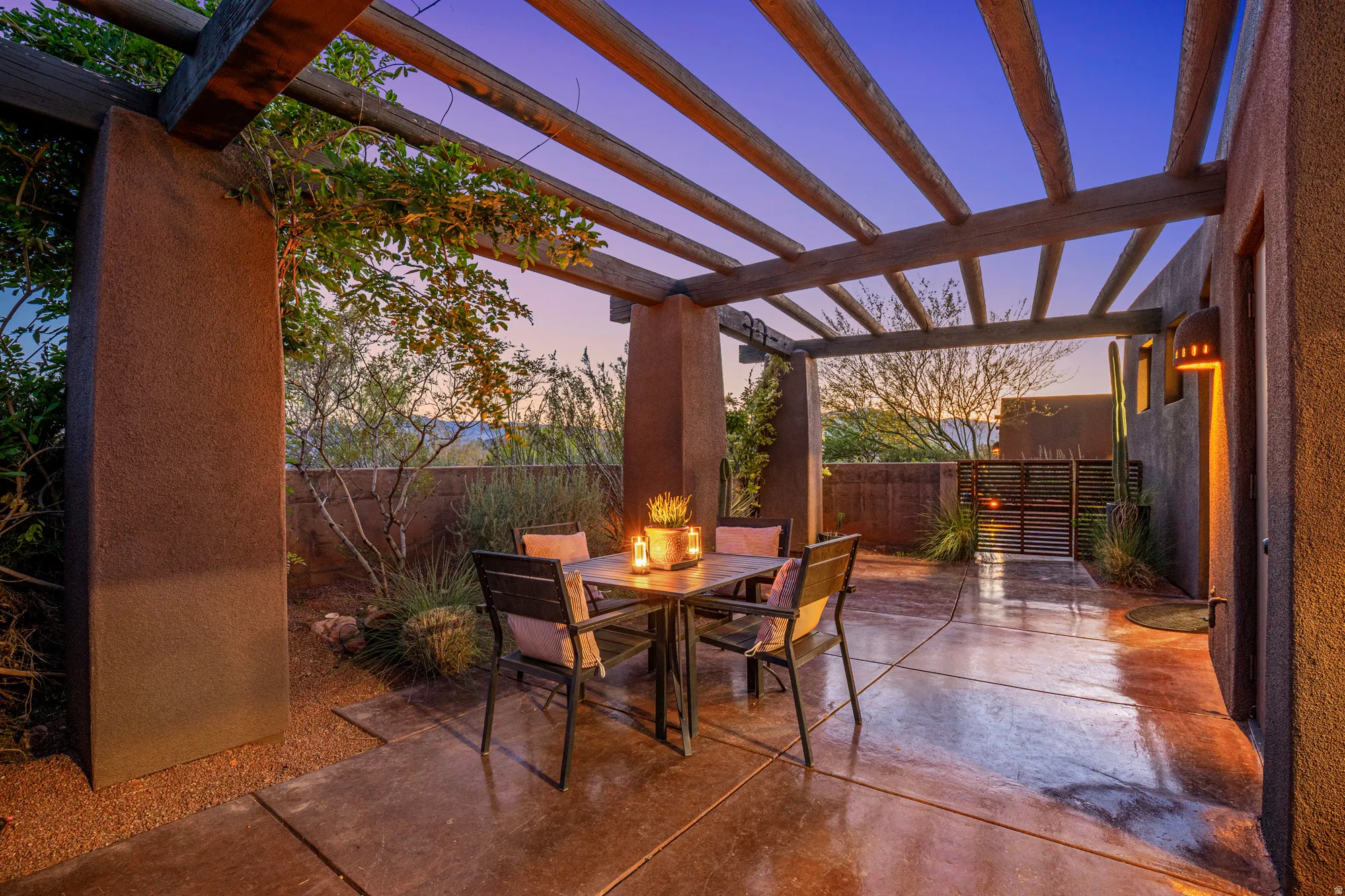 Paved patio featuring a wood pergola, stucco columns, and an integrated wall lantern