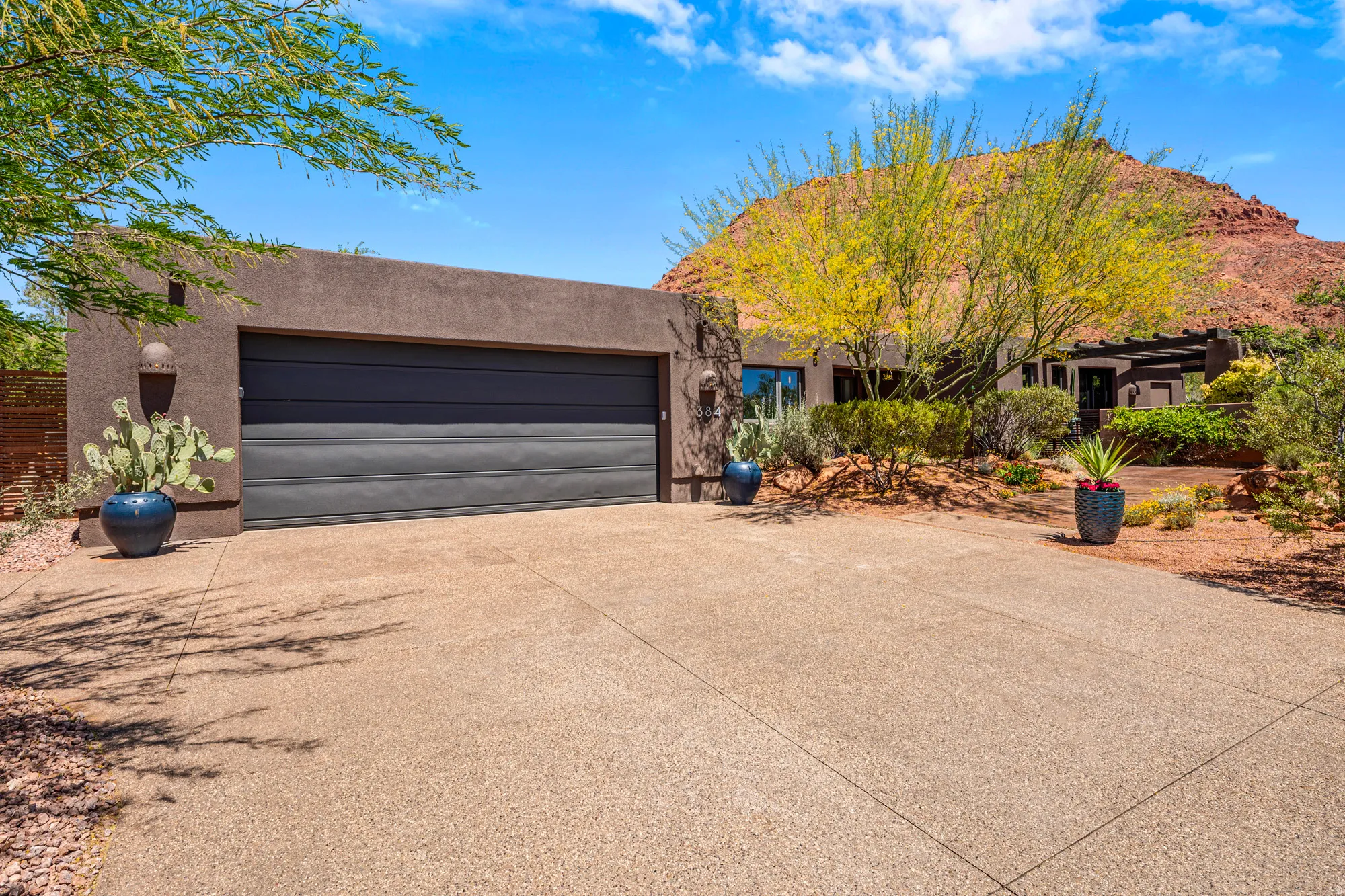 Desert contemporary residence featuring a stucco exterior and a dark paneled garage door