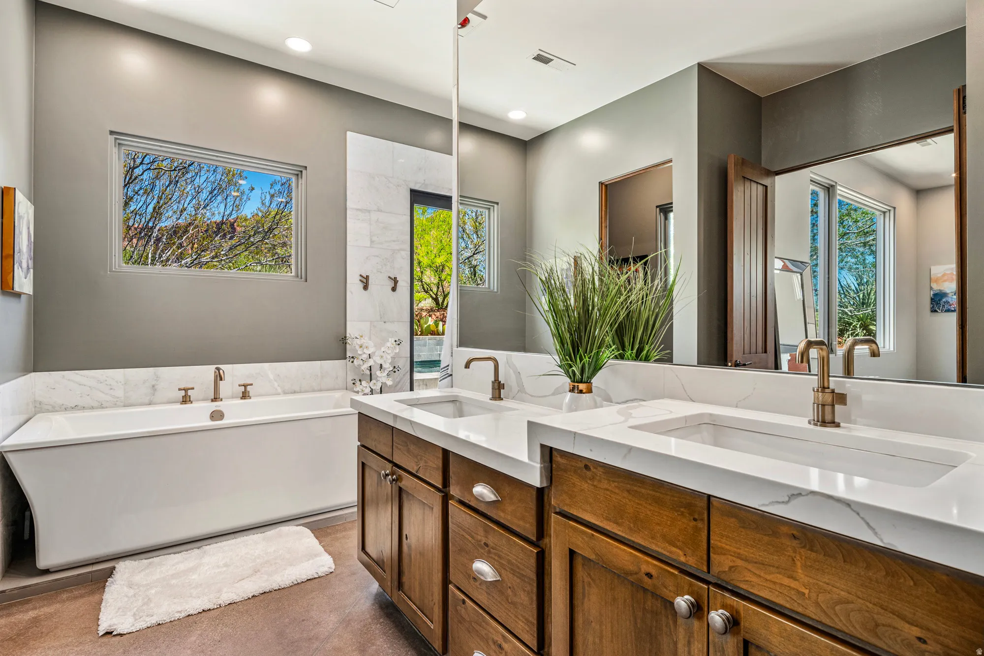 Bathroom featuring a freestanding soaking tub, dual vanity with undermount sinks, and stone countertops