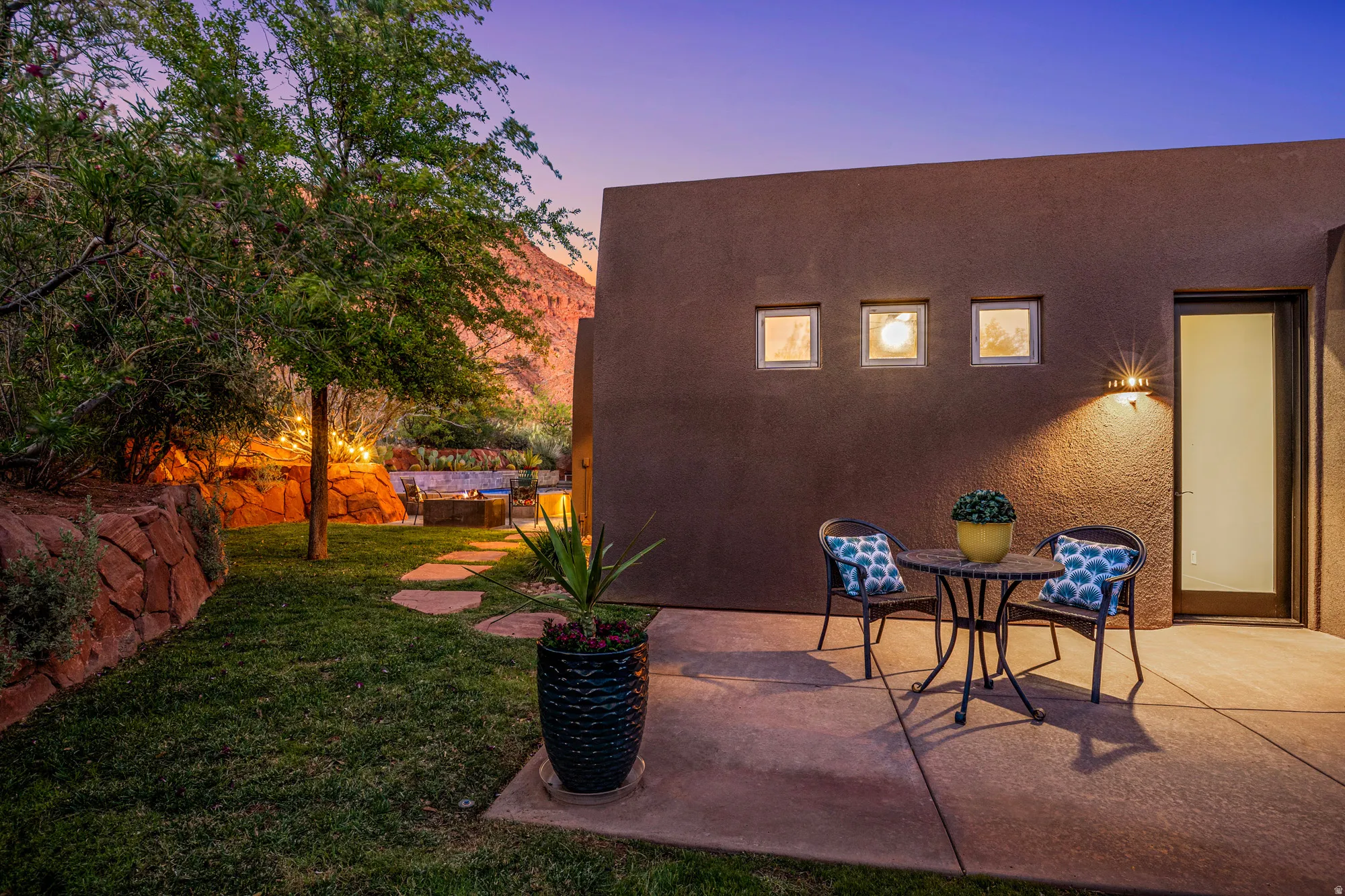 Exterior patio featuring a stucco finish, three square window accents, and a contemporary outdoor sconce