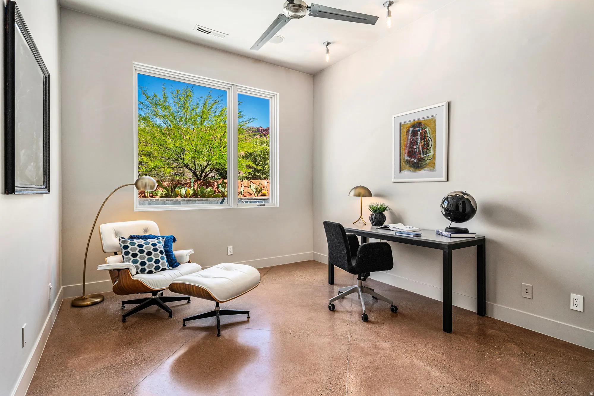 Office space featuring a large window, a sloped ceiling, and a ceiling fan with track lighting