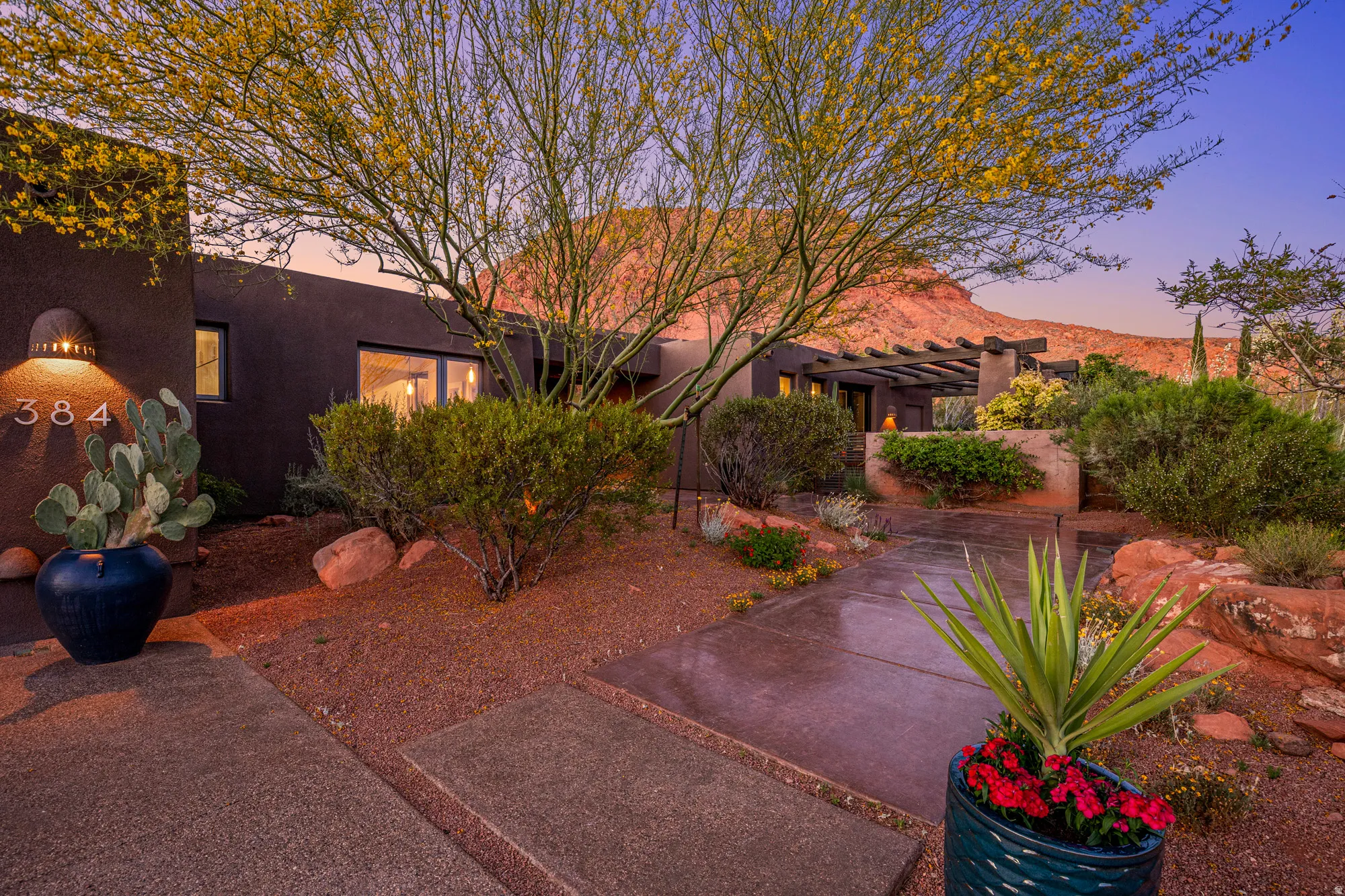 Southwestern-style residence featuring a dark stucco exterior and a pergola-covered patio