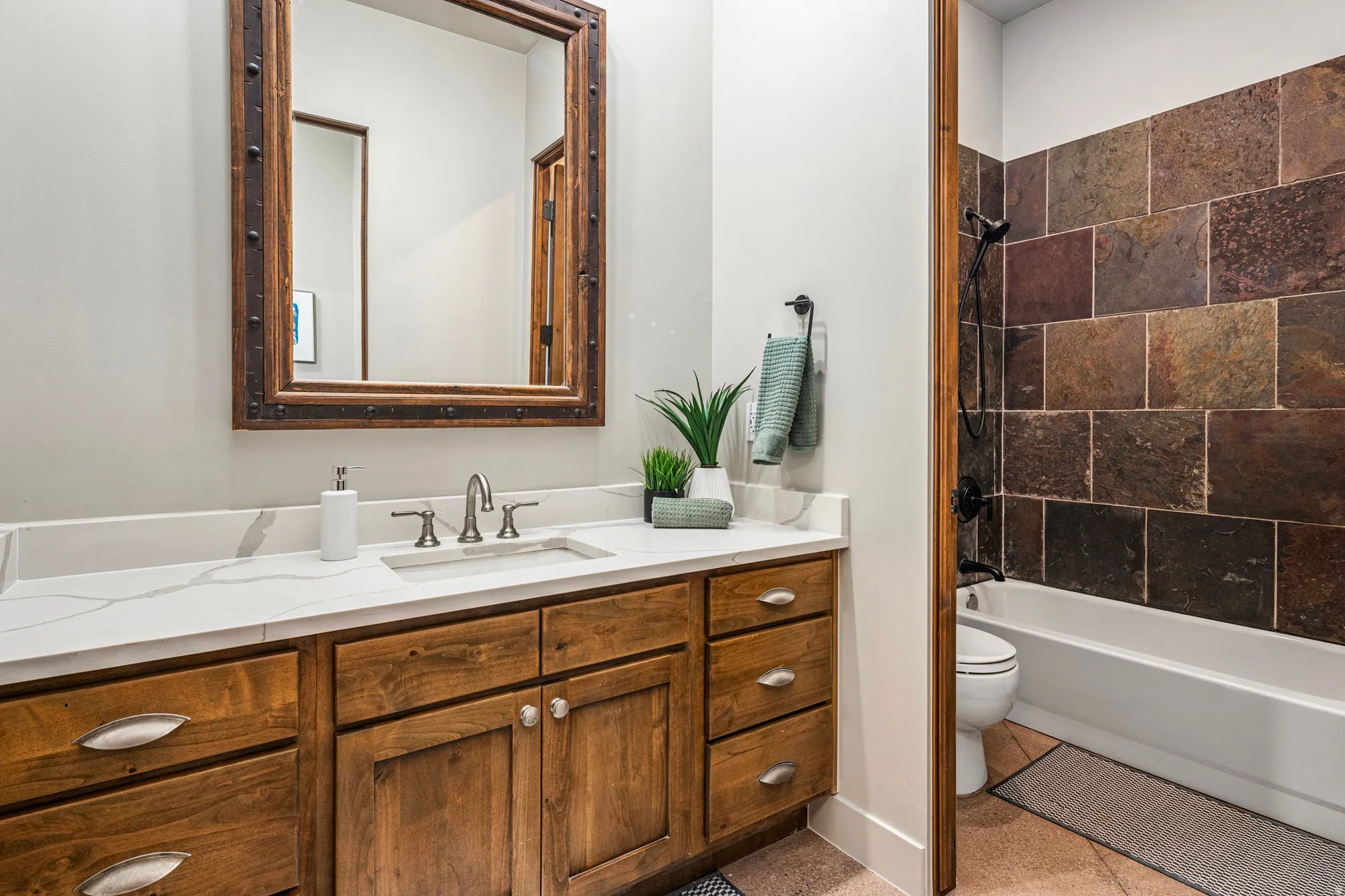 Bathroom featuring a wood vanity with a white countertop, undermount sink, and a framed mirror