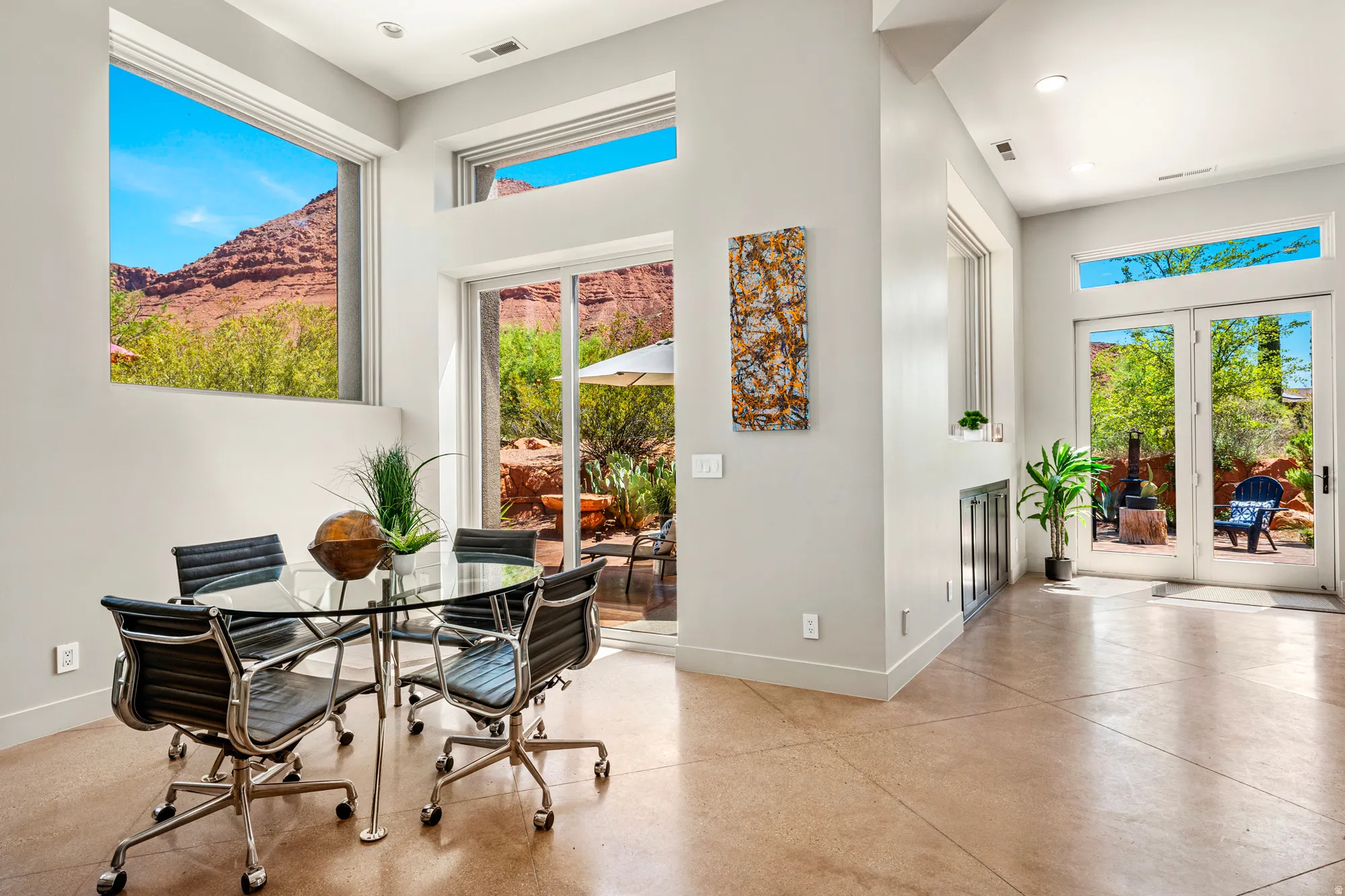Open concept living area featuring expansive windows, glass sliding doors, and glass paneled double doors