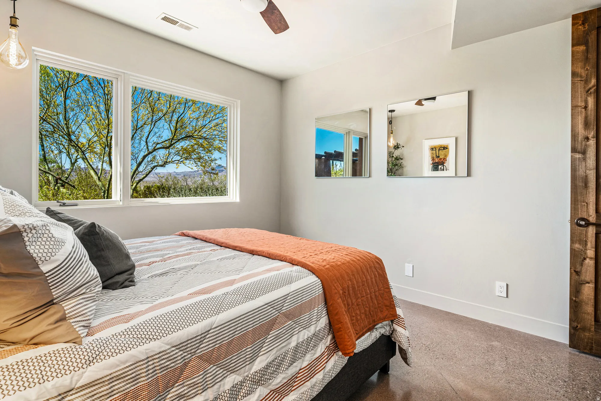 Room featuring large windows, wood-finish flooring, a ceiling fan, and a wood-paneled door with a dark handle